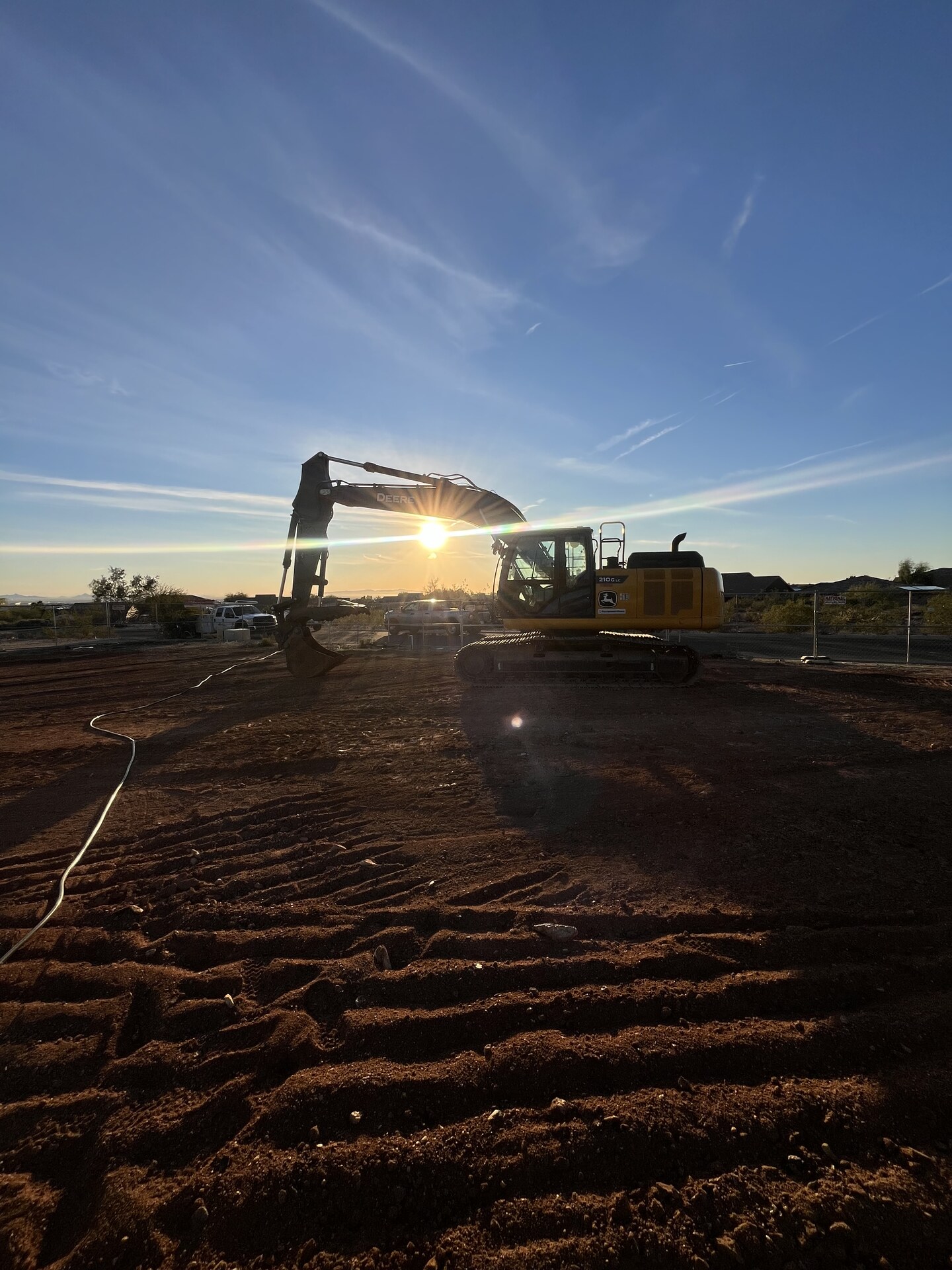 Excavator digging trench at sunset